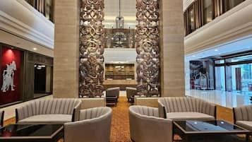 A lobby with a central seating area, a decorative wall, and a view of the outside.