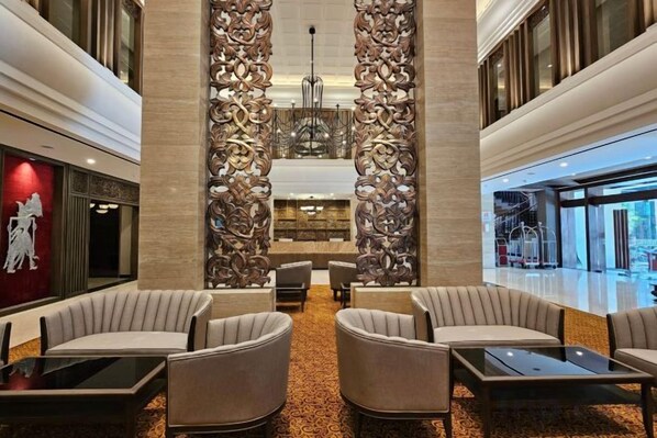 A lobby with a central seating area, a decorative wall, and a view of the outside.