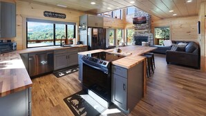 Una cocina moderna con una isla central, electrodomésticos integrados y una chimenea de piedra.