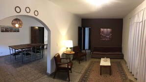 Una sala de estar con un sofá, sillas, una mesa de centro y un comedor con una mesa y sillas.
