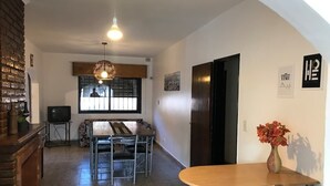 Un espacio habitable compacto con comedor, televisión y mostrador de cocina.