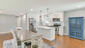 A modern kitchen with white cabinetry, stainless steel appliances, and a blue cabinet. - Hampton Bays Retreat: Walk to Squires Beach! (Hampton Bays)