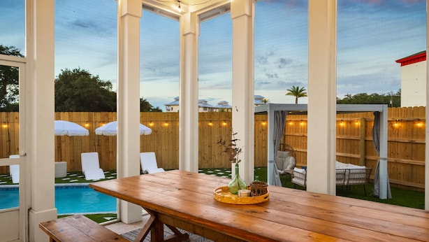 Un patio al aire libre con una mesa y sillas de madera, y una piscina.