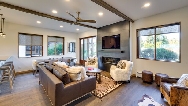 A spacious living room with a fireplace, large windows, and a modern ceiling fan. - Sun Valley Condo w/ Furnished Patio: Near Skiing! (Sun Valley)