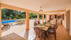 An outdoor patio with a dining table, chairs, and a pool in the background. - Villa Ca Na Francisca - By Dream Villas Pollensa (Pollensa)