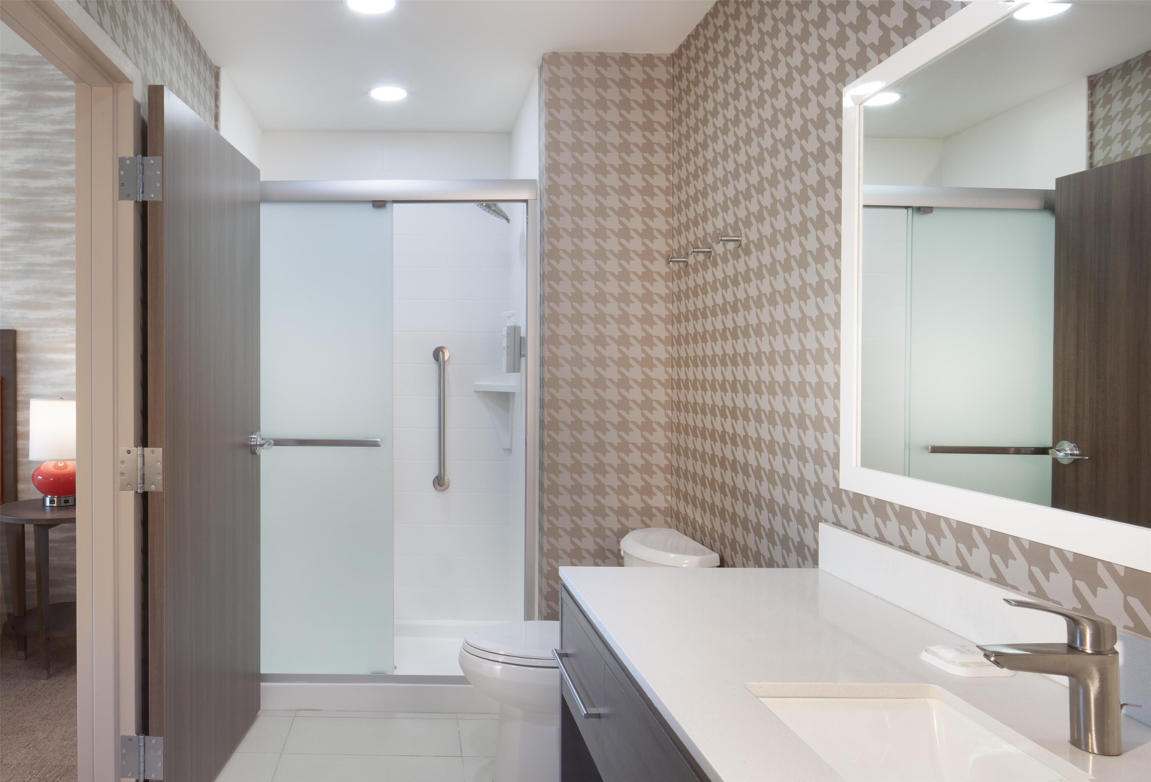 A modern bathroom with a shower, toilet, and vanity.