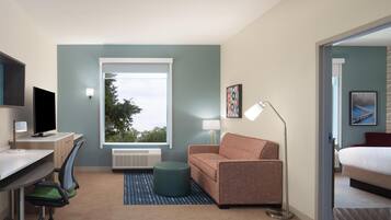 Una habitación de hotel moderna con escritorio, silla de oficina, sofá y cama.