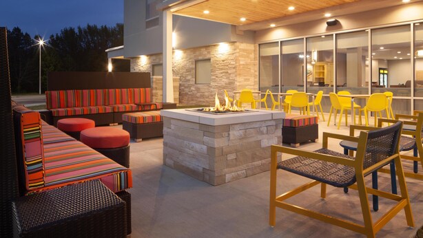 An outdoor seating area with wicker furniture and a stone fire pit. - Home2 Suites By Hilton Jackson (Jackson)