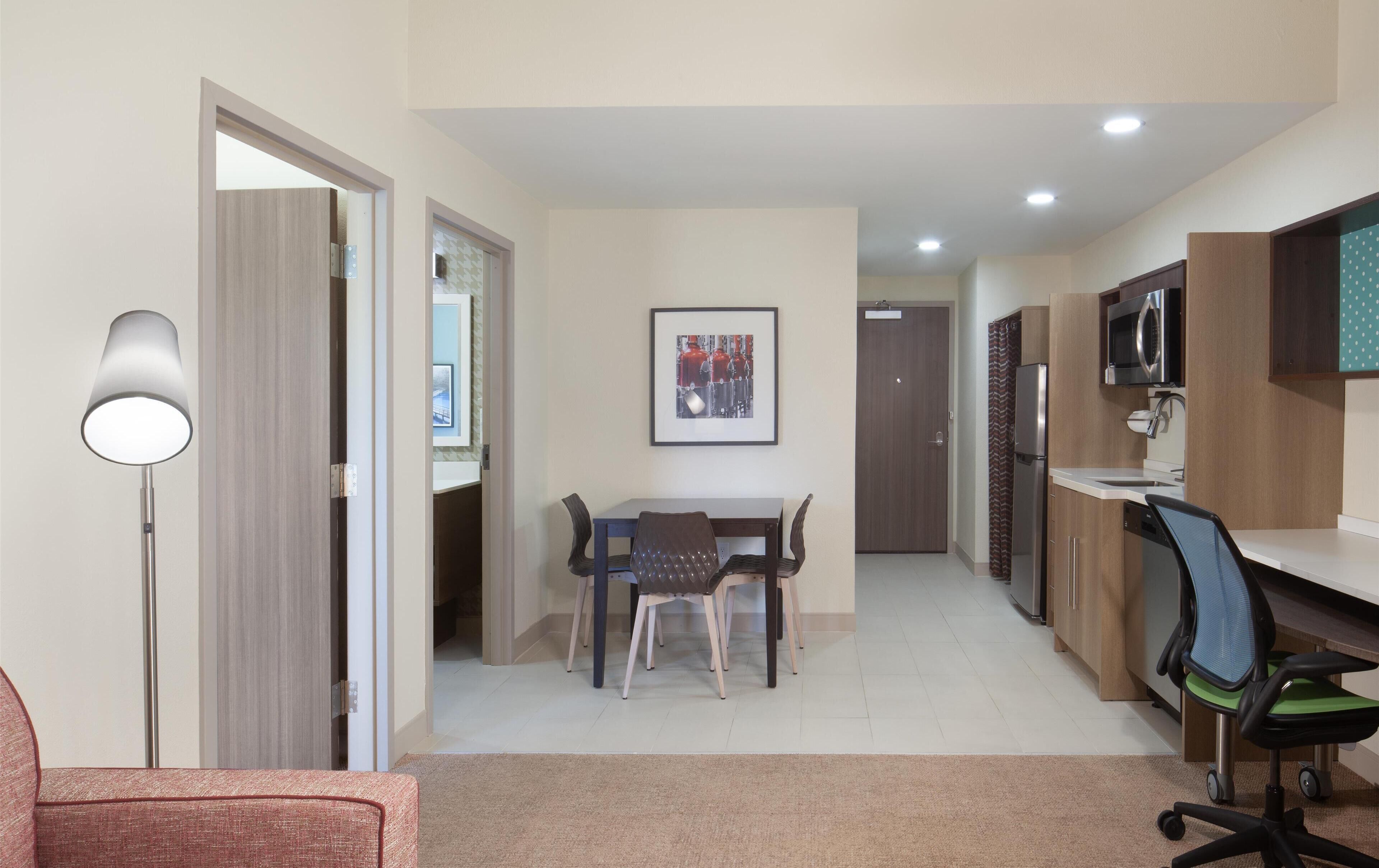 A modern kitchen with a dining area, a refrigerator, microwave, and a chair.