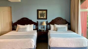 A hotel room with two beds, a nightstand with a lamp, and a framed picture on the wall.