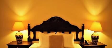 A hotel room with a bed, two bedside tables with lamps, and a headboard.