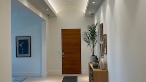 Ein moderner Flur mit einer Holztür, einem Konsolentisch mit Dekoration und einem gerahmten Bild an der Wand.