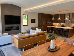 Una sala de estar moderna con un sofá, una mesa de comedor y un televisor montado en la pared.