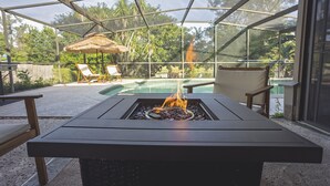 An outdoor patio with a fire feature, lounge chairs, and a pool.