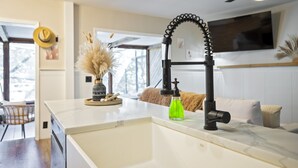 A kitchen with a white marble countertop, a black faucet, and a ceiling fan.