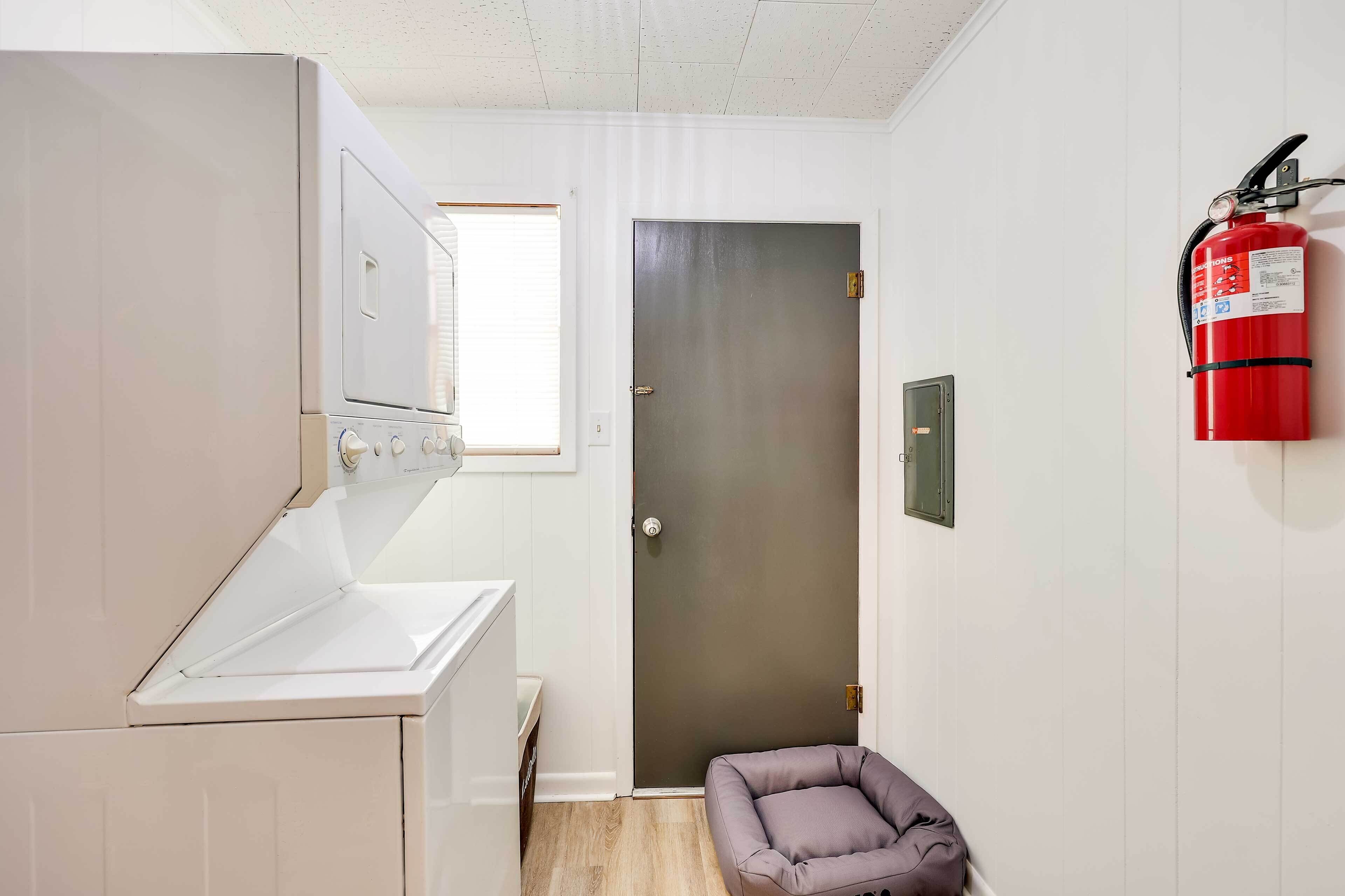 A laundry area with a washing machine, a door, and a fire extinguisher.