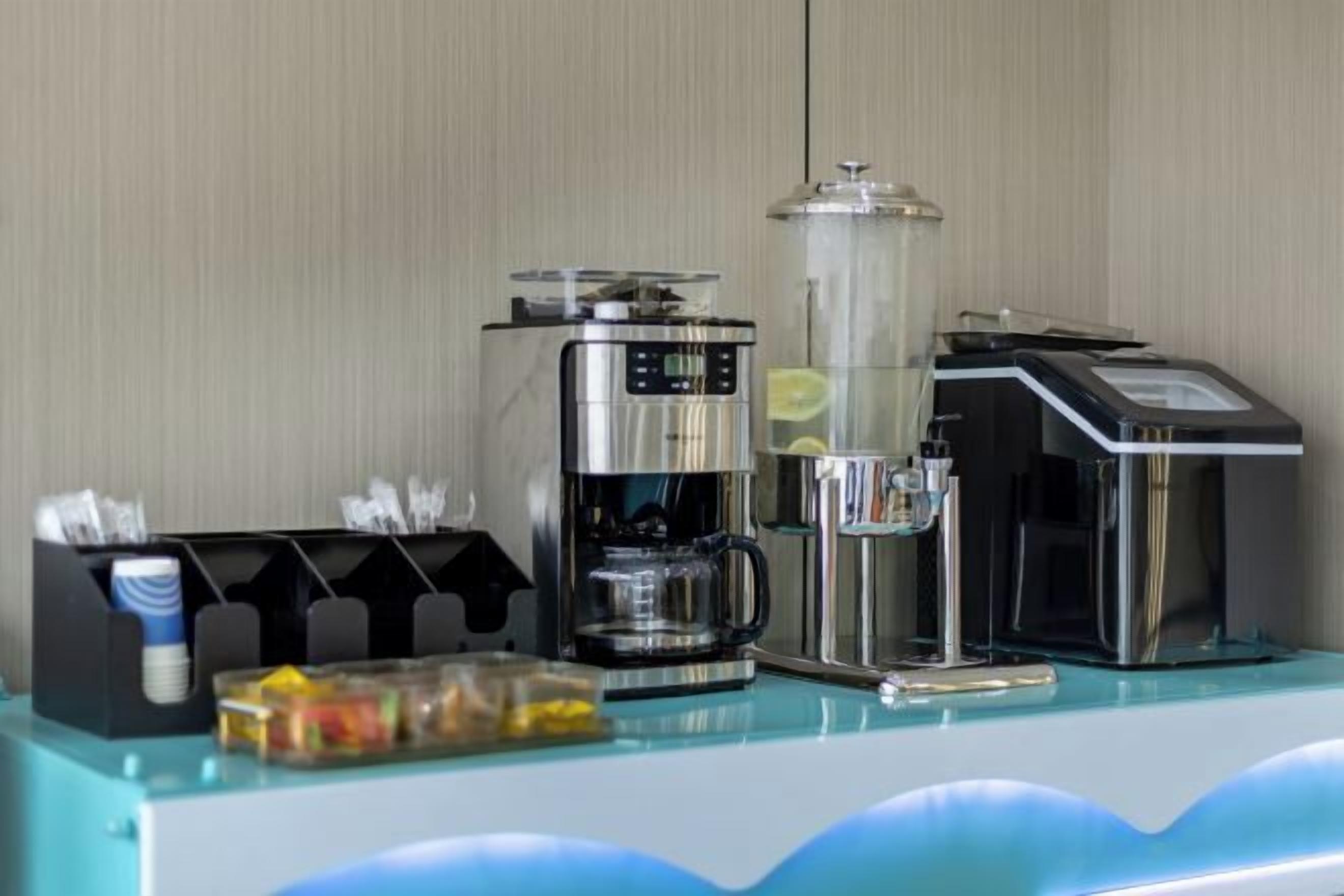 Een koffiehoek met een koffiezetapparaat, een melkopschuimer en een koffieautomaat.