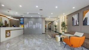 A modern hotel lobby with a reception desk, seating area, and a digital cityscape display. - Elong ME Hotel (Binhai High-Speed Railway Station) (Tianjin)