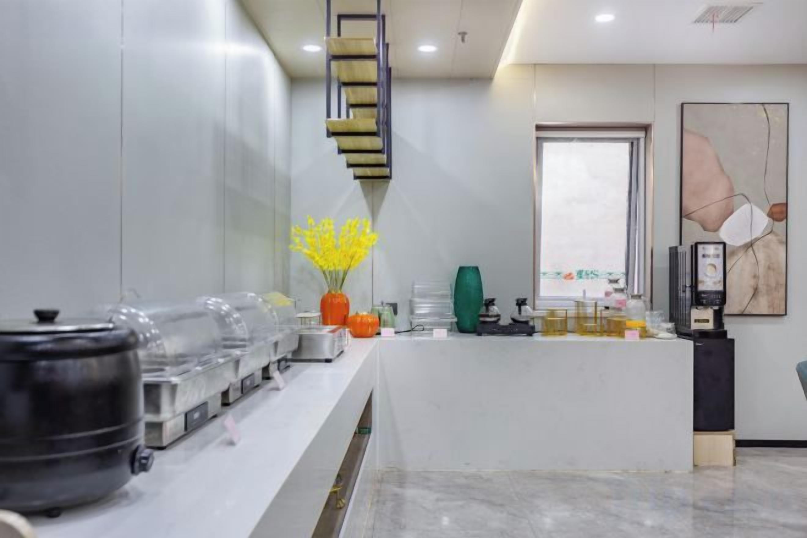 A reception area with a counter, a coffee machine, and a vase with yellow flowers.