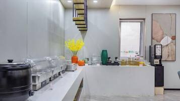 A reception area with a counter, a coffee machine, and a vase with yellow flowers.