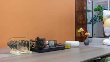 A table with a tray of items, a vase with flowers, and a bookshelf with books and decorative items.