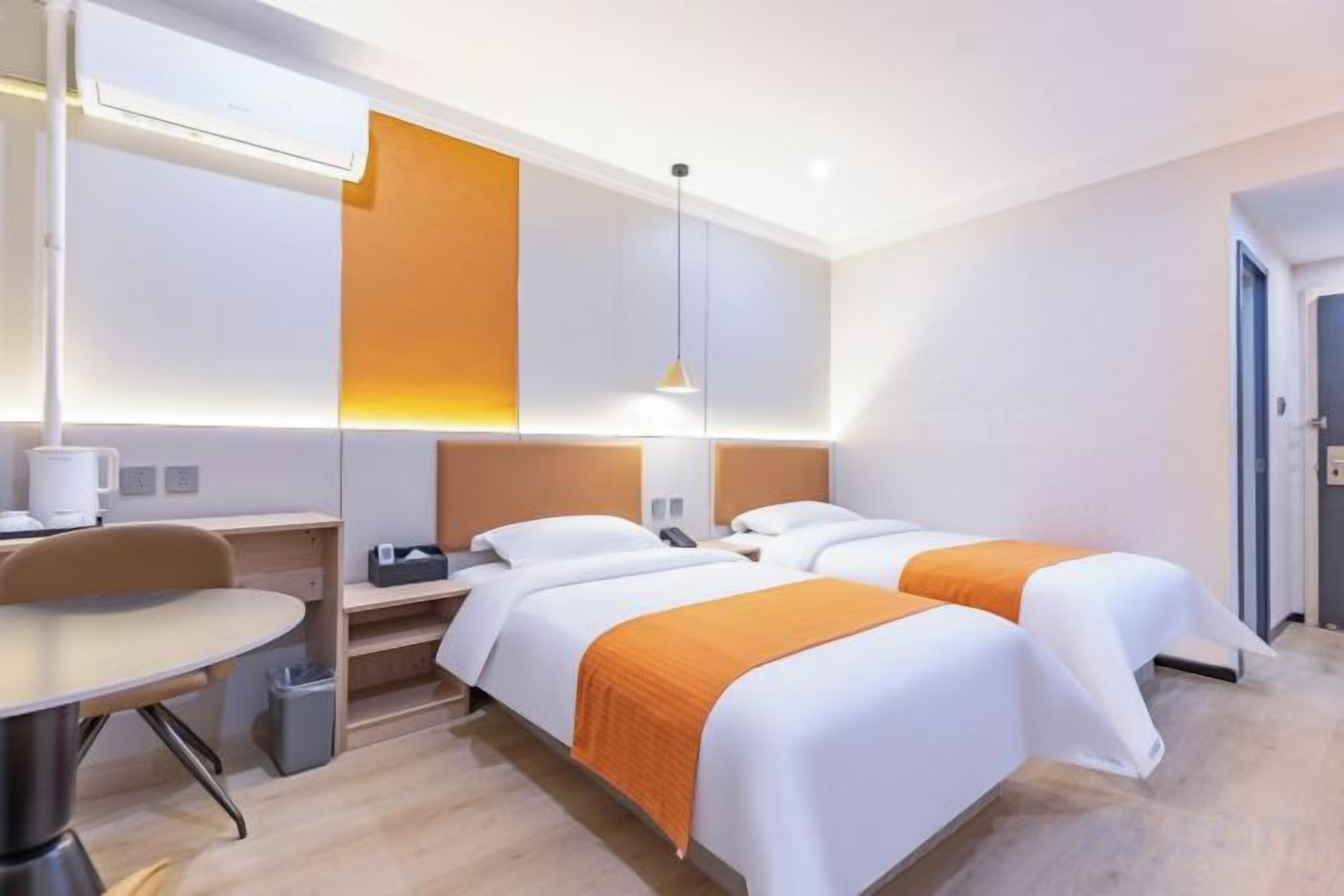 Une chambre d’hôtel avec deux lits, un bureau et une chaise.
