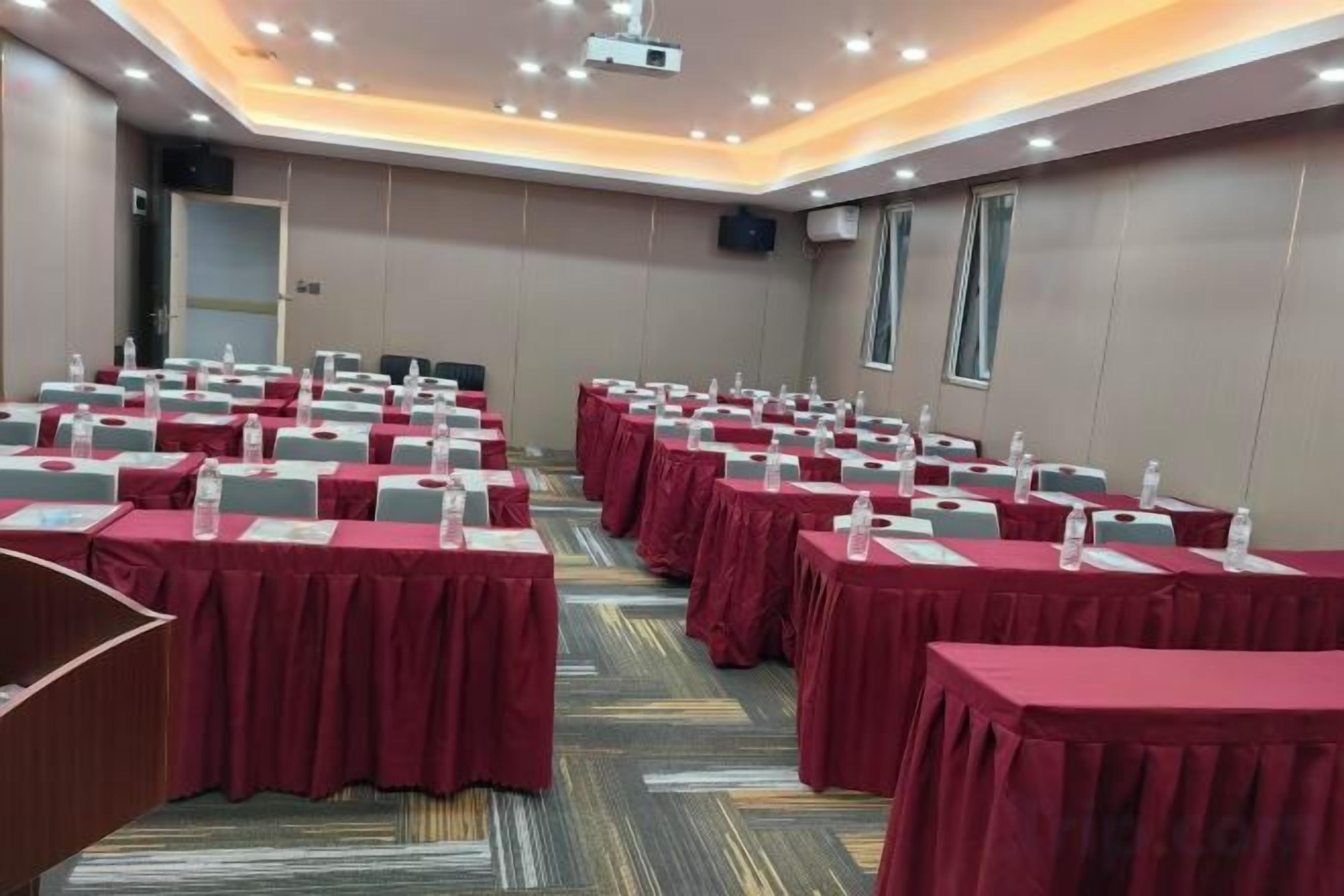 A conference room with multiple tables, each with a red tablecloth and water bottles.