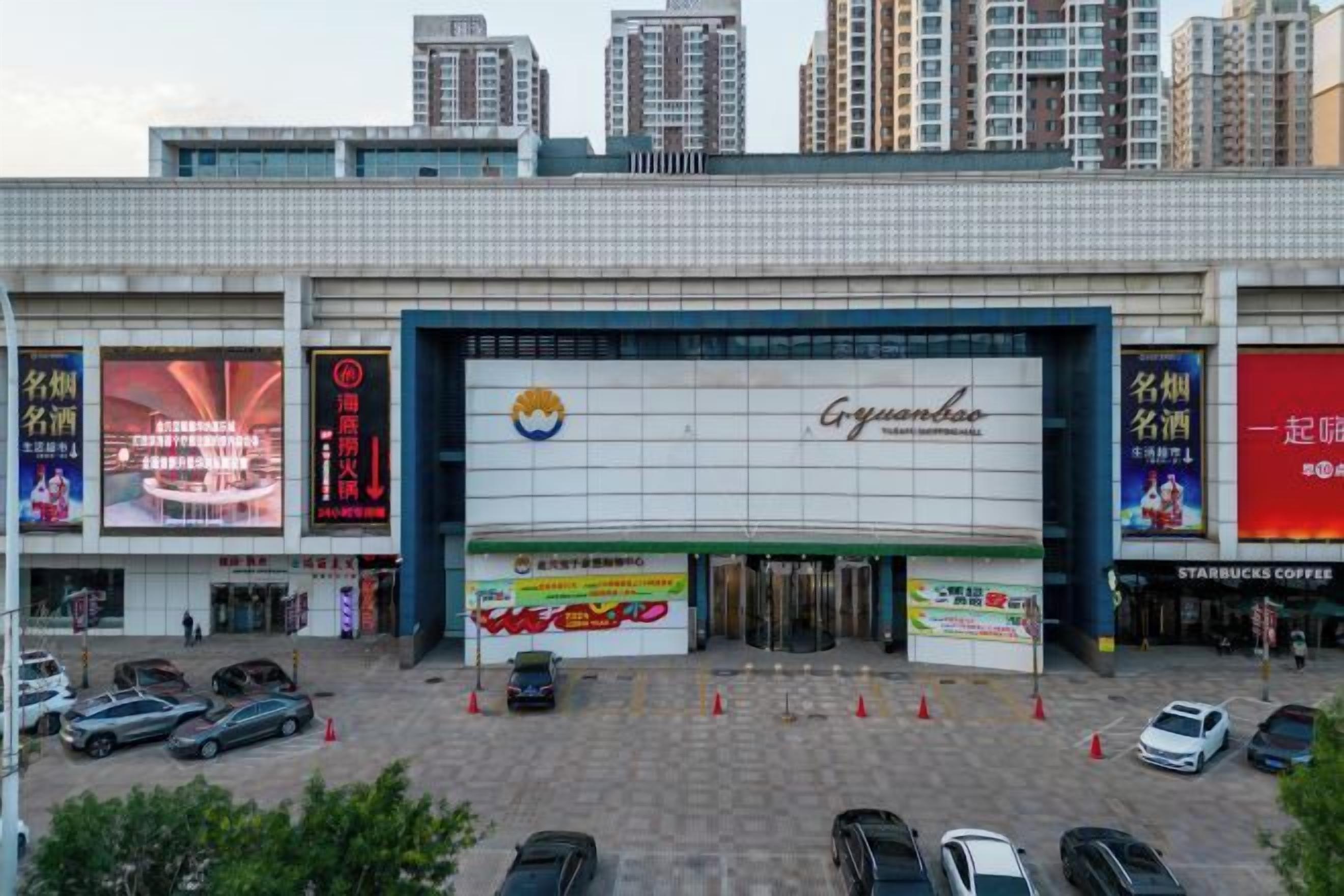 A commercial building with a large sign for Gungdoh, multiple storefronts, and a parking lot with cars.