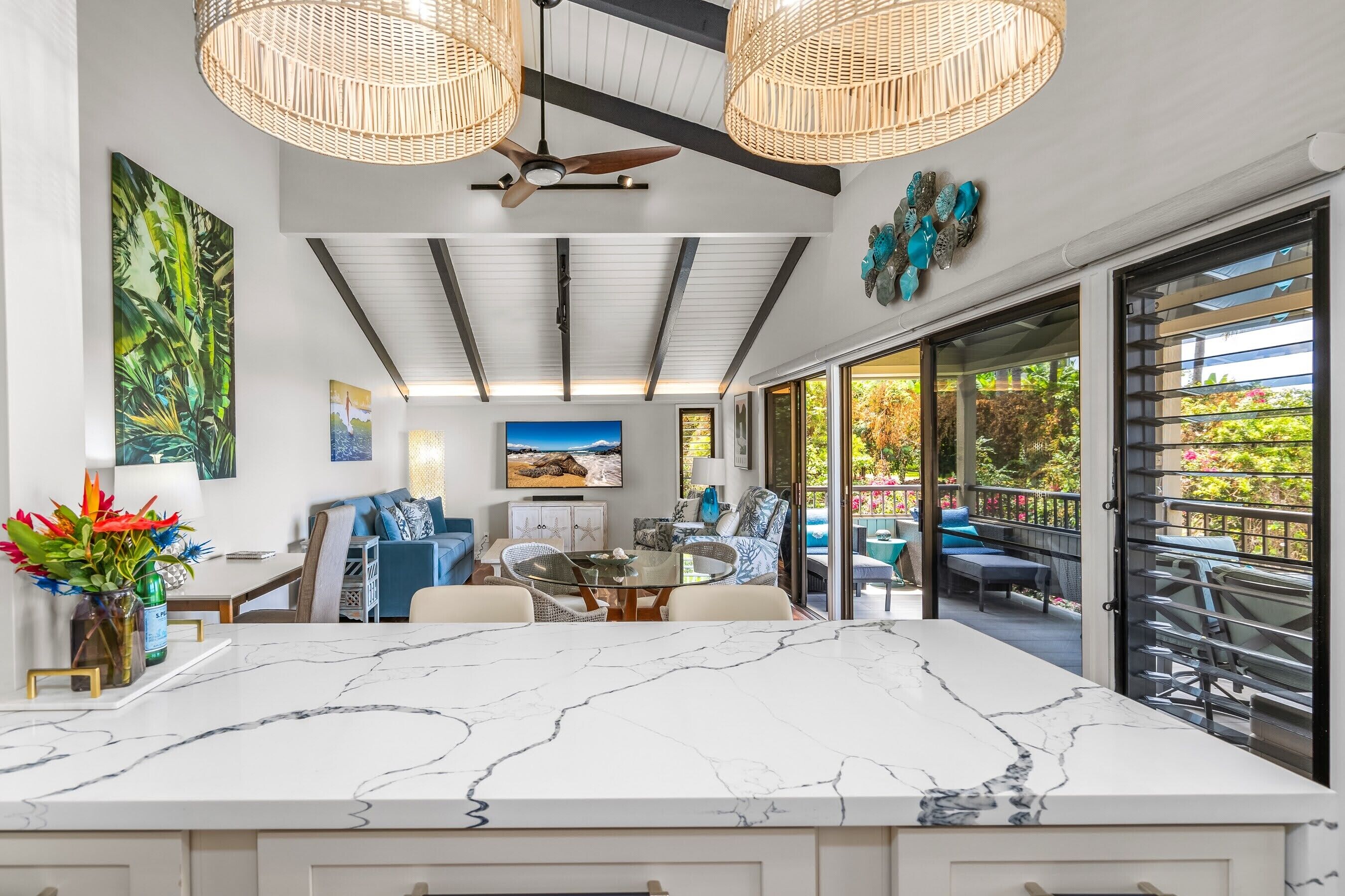 A spacious kitchen with a marble countertop, a dining area with a round table, and a view of the outdoor patio.