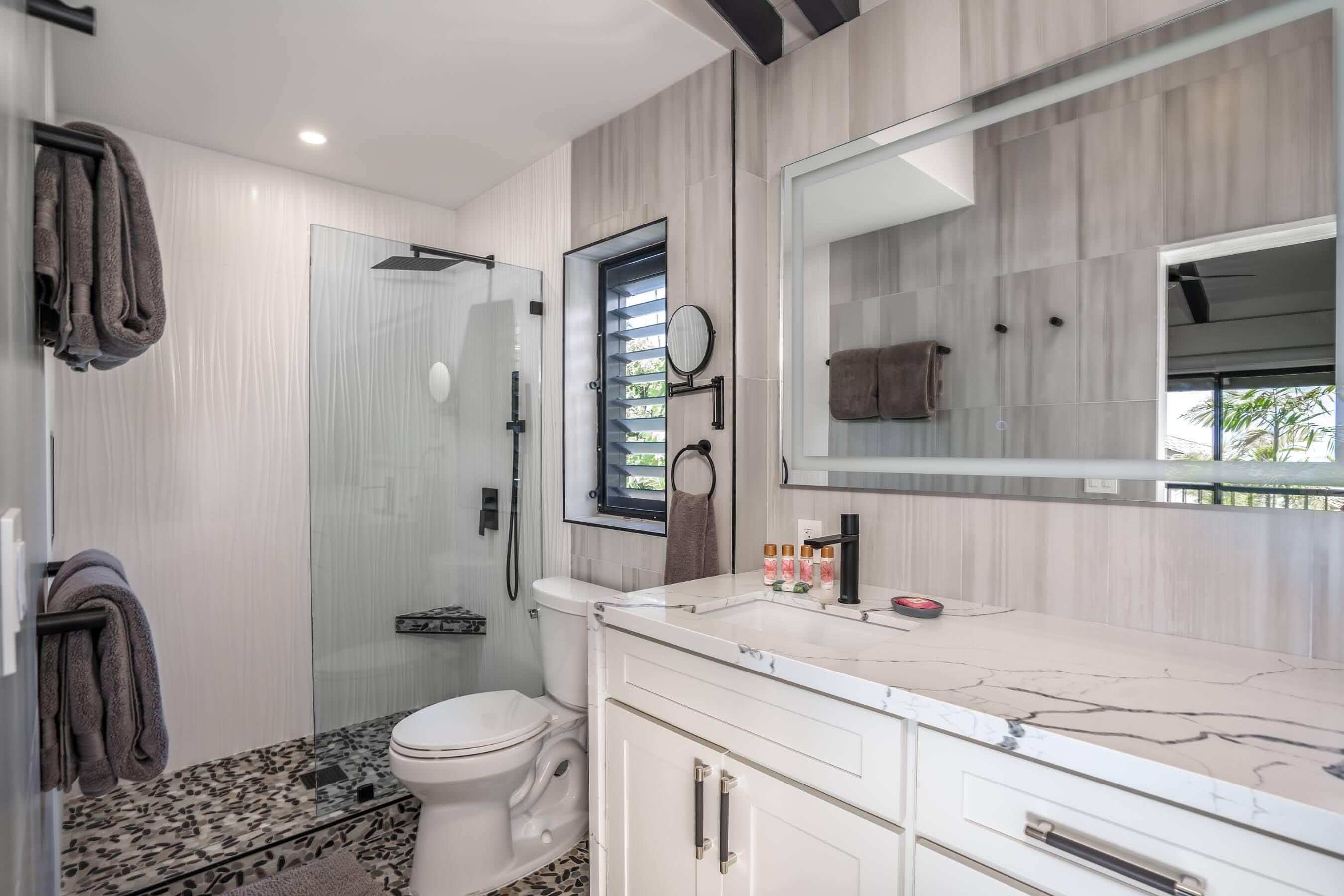 A modern bathroom with a toilet, shower, and vanity with a mirror.