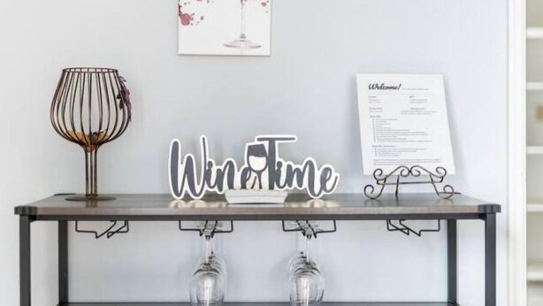 A table with a 'Wine Time' sign, a framed menu, and two wine glasses. - Clean&Cozy 3 bedroom 2 bath home No cleaning fees
 (Fresno)