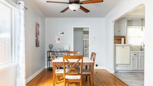 A dining area with a wooden table and chairs, a ceiling fan, and a view into the kitchen. - Clean&Cozy 3 bedroom 2 bath home No cleaning fees
 (Fresno)