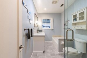 A bathroom with a glass shower enclosure, a white toilet, and a vanity with a mirror. - Clean&Cozy 3 bedroom 2 bath home No cleaning fees
 (Fresno)