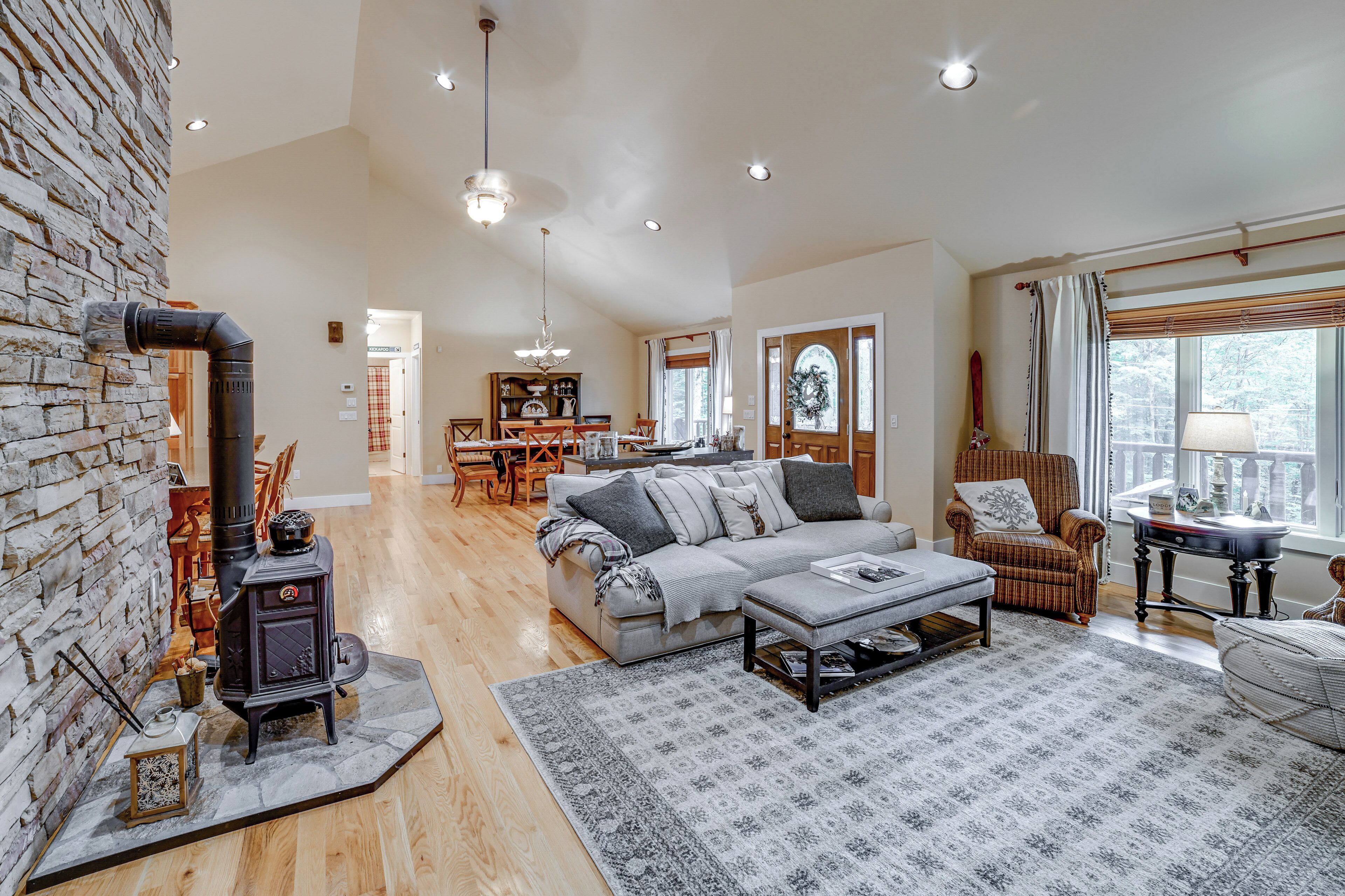 A spacious living room with a fireplace, a sofa, and a dining area in the background.