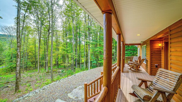 Eine Holzhütte mit Veranda und Blick auf einen Wald.
