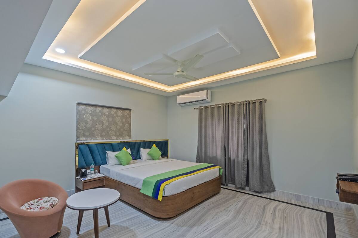 A modern bedroom with a bed, a chair, a small table, and a ceiling fan.
