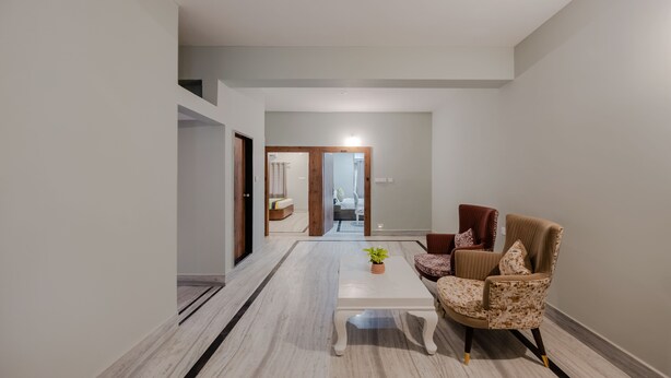 A spacious hallway with a marble floor, a white coffee table, and a patterned armchair. - Itsy Hotels Greenland Jungle View (Bhubaneshwar)