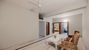 A modern living room with a white coffee table, a patterned armchair, and a ceiling fan. - Itsy Hotels Greenland Jungle View (Bhubaneshwar)
