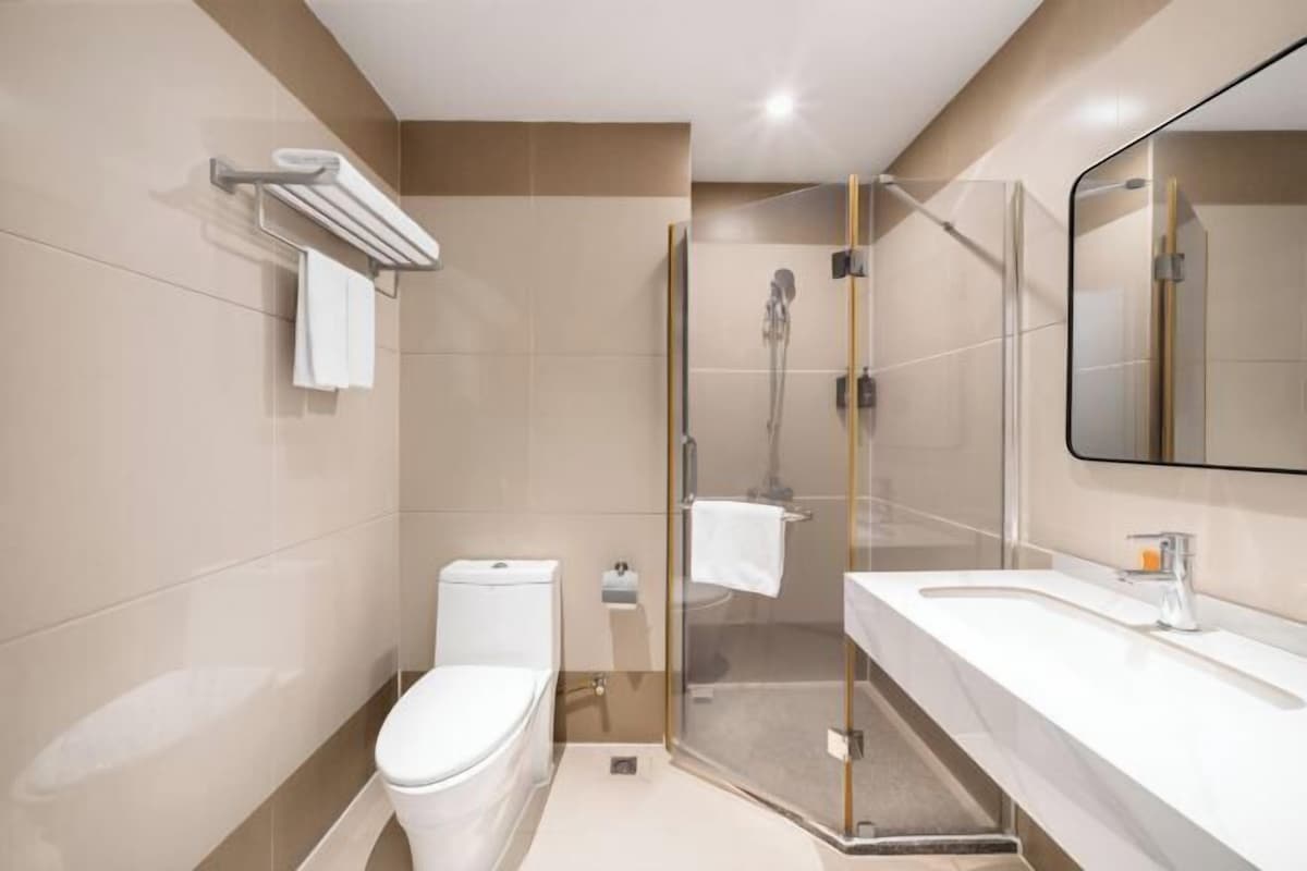 A modern bathroom with a toilet, shower, and sink.