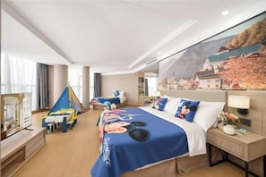 Habitación de hotel con una cama grande, un escritorio y una silla. Hay un mural en la pared y una ventana con cortinas.