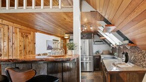 Eine rustikale Küche mit Holzschränken, einer Bar mit Hockern und einer Küchenwand aus Stein.