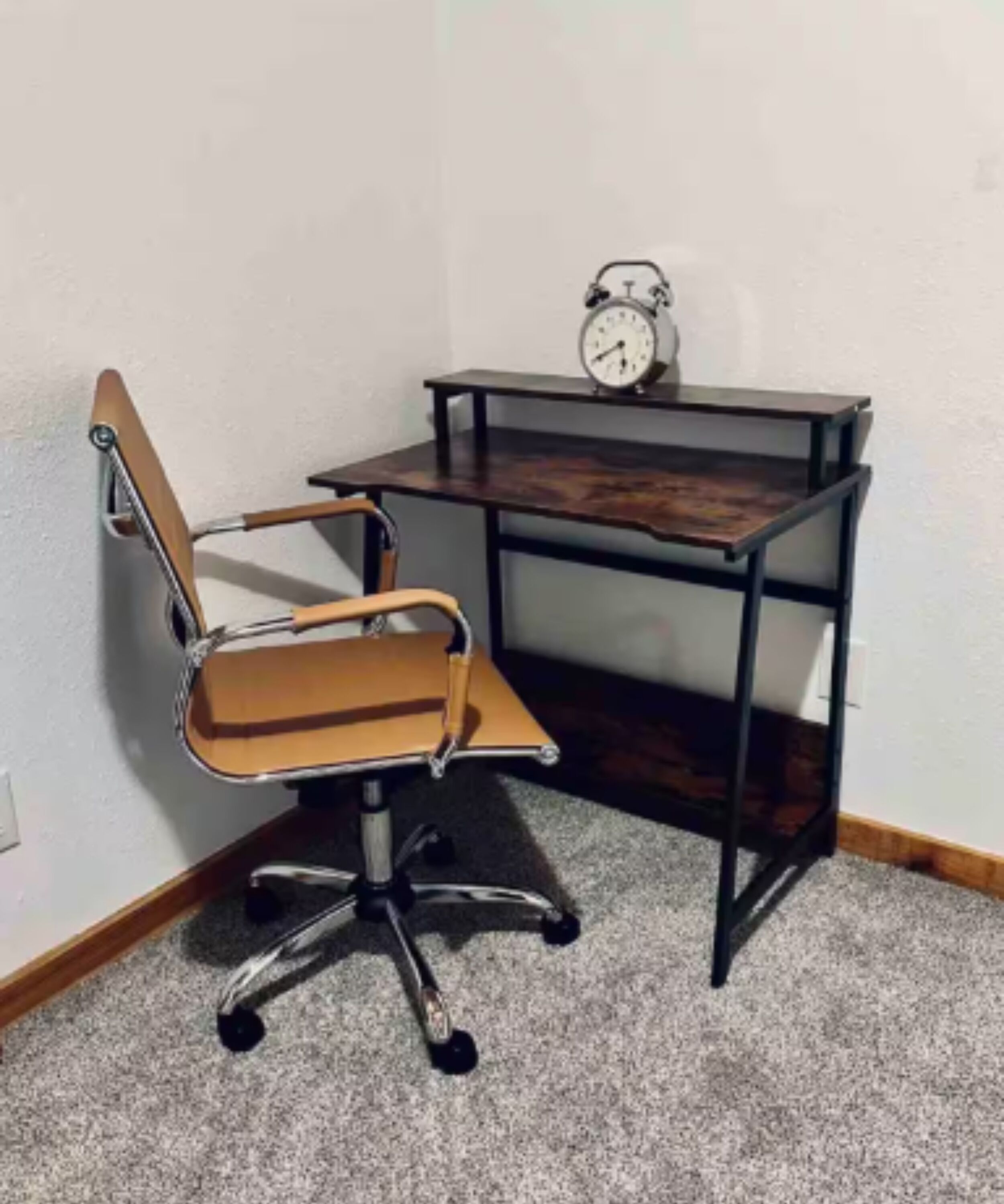 Ein Büro mit Ecke, ausgestattet mit einem Holzbüro, einem Stuhl und einer Wanduhr.