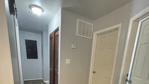A hallway with wooden flooring, white walls, and a door on the right.
