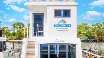 A white boat with three Baxi air conditioning units, a Dolphin's Vacation Rentals logo, and a nameplate reading "Atlantis".