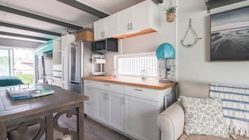 A compact kitchen with white cabinets, a wooden countertop, and a built-in microwave.