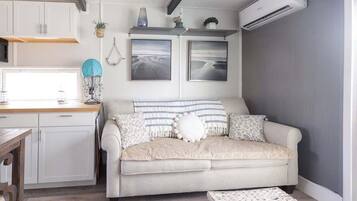 A modern living room with a sofa, a coffee table, and a kitchen area with cabinets and a countertop.