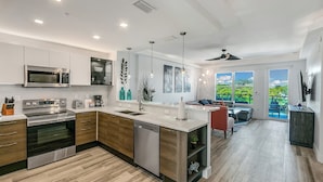 A modern kitchen with a central island, built-in appliances, and a dining area with a view. - Dolphins Vacation Rental  (Merritt Island)