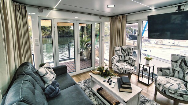 A modern living room with a grey sofa, patterned armchairs, a coffee table, and a TV. - Dolphins Vacation Rental  (Merritt Island)