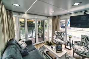 A modern living room with a grey sofa, patterned armchairs, a coffee table, and a TV. - Dolphins Vacation Rental  (Merritt Island)