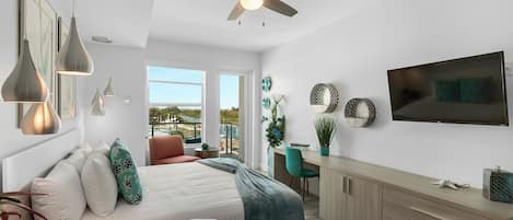 A modern bedroom with a bed, desk, and balcony view.